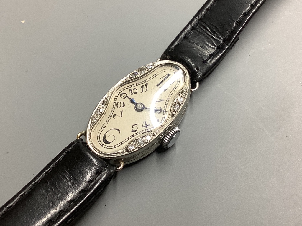 A lady’s mid 20th century white metal stamped platine and diamond set oval cocktail watch, on a leather strap.